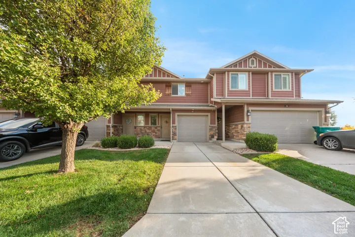 Two-story exterior featuring wood-composite siding, stone veneer accents, decorative gable detailing, and attached multi-car garages with concrete driveways