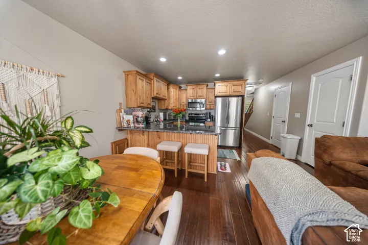 Kitchen featuring wooden cabinetry, stone-surface countertops, beadboard island detailing, recessed ceiling lighting, and wood-finish flooring