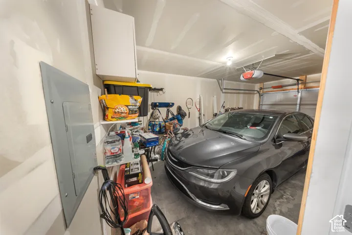 Enclosed garage featuring drywall finish, mounted electrical panel, and automatic overhead door opener