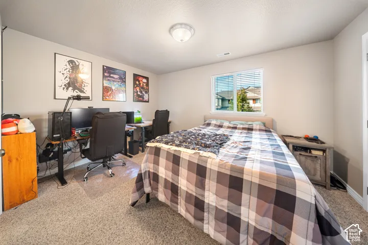Neutral-toned interior featuring wall-to-wall carpeting, a dual-pane window with horizontal blinds, and a circular flush-mount ceiling light fixture
