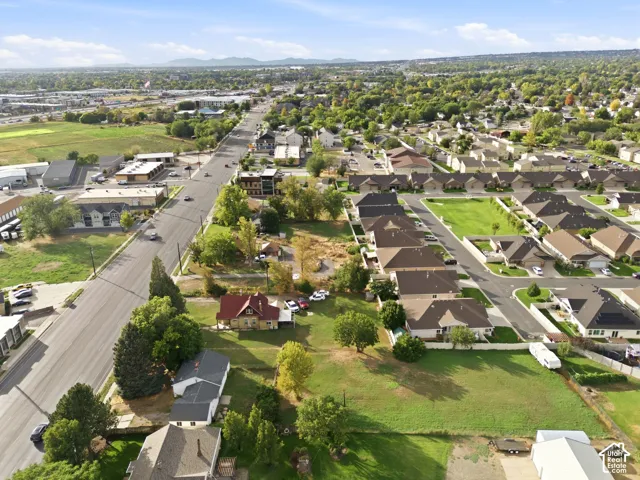 Aerial perspective of a corner lot property featuring expansive open grass space, mature trees, and proximity to major thoroughfares
