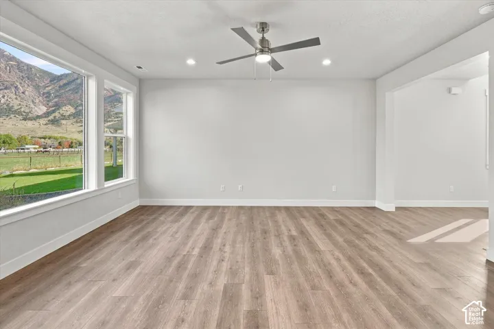 Living space featuring wood-finish flooring, recessed lighting, a ceiling fan with integrated light, and large windows showcasing a mountain backdrop