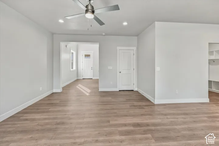 Neutral-toned interior featuring wood-finish flooring, recessed lighting, a brushed metal ceiling fan, and paneled doors
