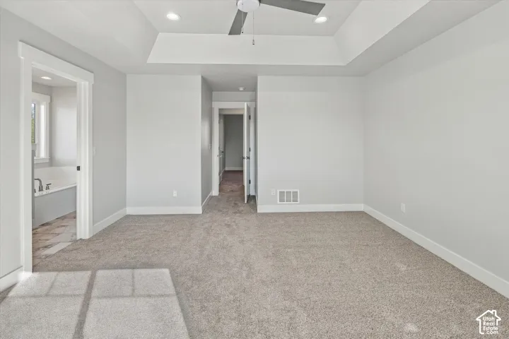 Room featuring a tray ceiling, recessed lighting, ceiling fan, and carpeted flooring