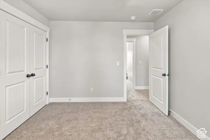 Interior room featuring wall-to-wall carpeting, neutral-toned walls, white two-panel doors, and white door casings