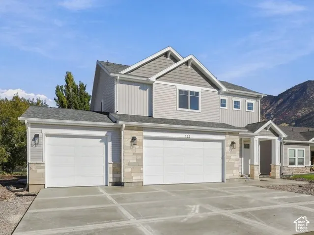Two-story residence with a three-car garage, stone veneer siding, and mountain backdrop