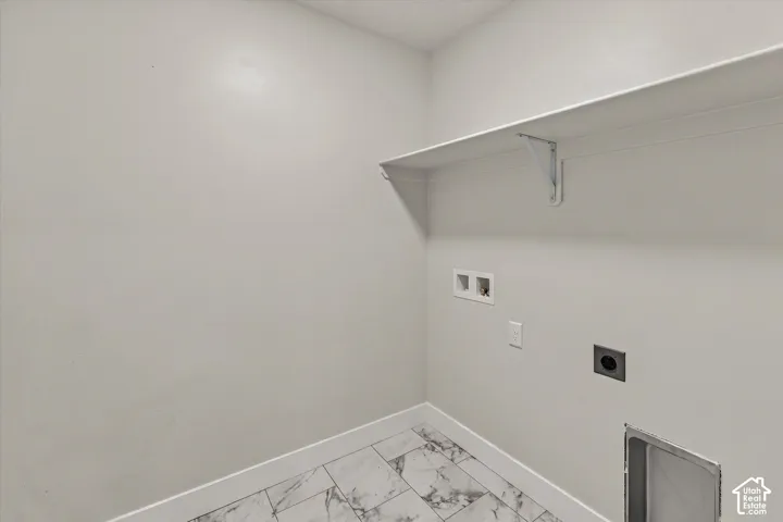 Utility area featuring large-format tile flooring with stone-pattern finish, wall-mounted shelving, and dedicated washer and dryer hookups