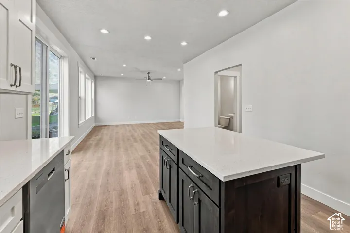 Kitchen featuring a dark-toned center island with a quartz countertop, wood-finish flooring, recessed lighting, and multiple windows