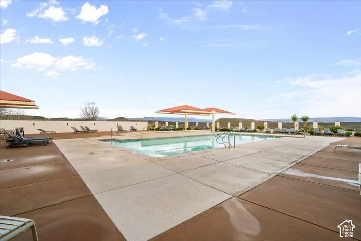 Outdoor swimming pool featuring a concrete deck, built-in structural shade canopies, and a masonry perimeter wall