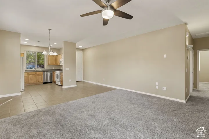 Open concept area featuring neutral carpeting, tile flooring, a brushed nickel ceiling fan with integrated light, and recessed lighting