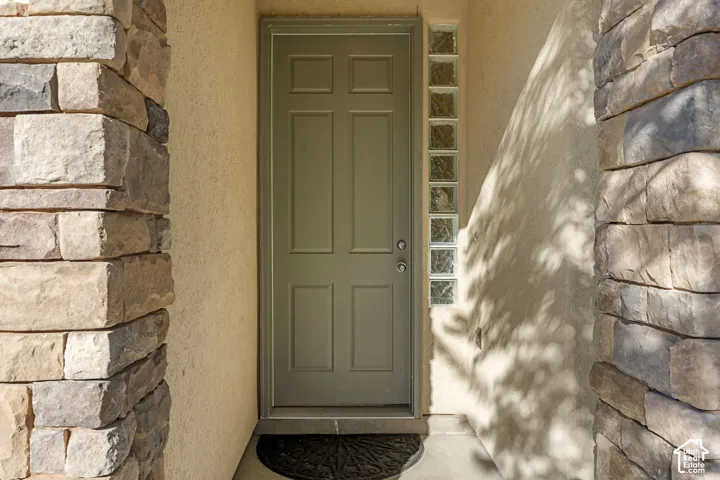 Entryway featuring stacked stone pillars, a six-panel door, and vertical glass block sidelight