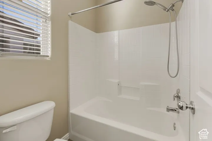 Full-height tiled tub surround with integrated shelving, chrome shower fixtures, and horizontal blinds