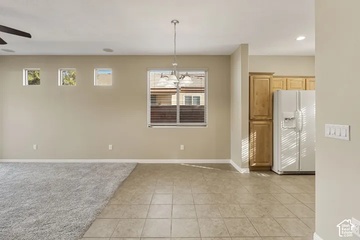Neutral-toned interior featuring square tile flooring, wall-to-wall carpeting, wood-finish cabinetry, a multi-light chandelier, and high-placed transom windows