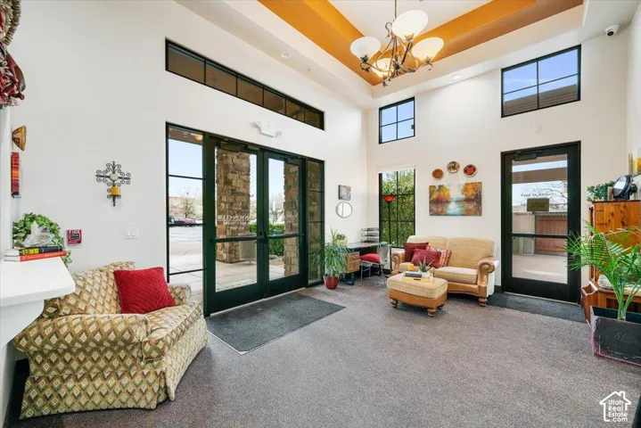 Entryway featuring soaring ceilings, a recessed tray ceiling, tiered chandelier, expansive multi-pane windows, and dual glass-paneled entry doors