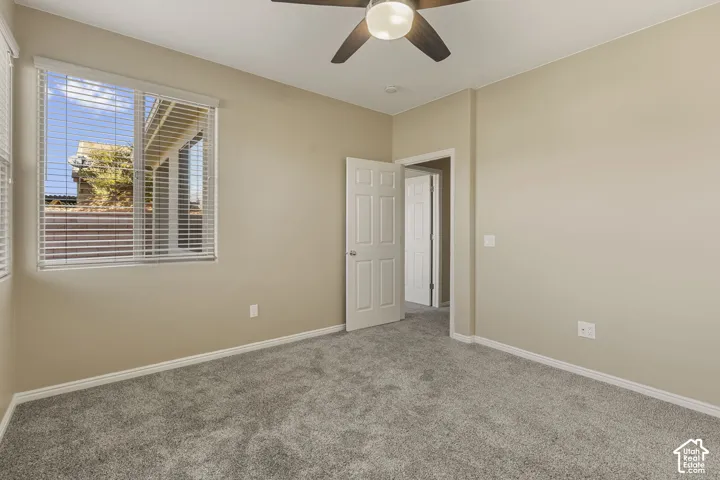 Neutral wall-to-wall carpeting, multi-panel interior door, and ceiling fan with integrated light fixture