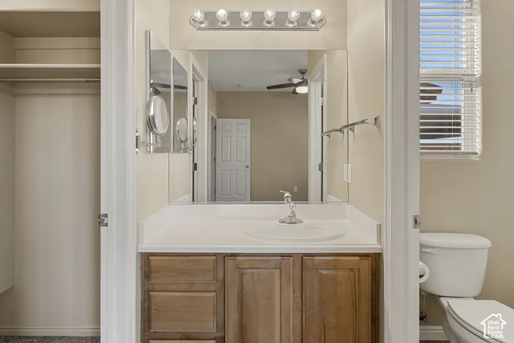 Bathroom vanity featuring wood-finish cabinetry, a white countertop with an integrated circular sink, polished chrome faucet, expansive wall-mounted mirror, and multi-bulb vanity lighting