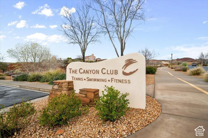 Community signage for The Canyon Club featuring tennis, swimming, and fitness facilities with stone masonry accents and desert landscaping