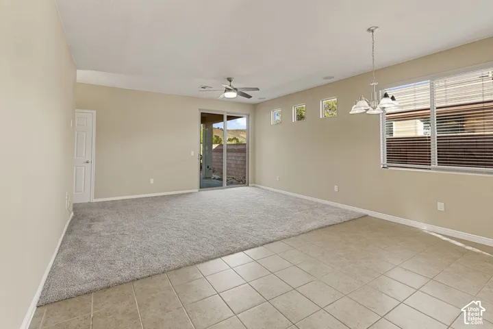 Open-concept interior featuring neutral wall tones, ceramic tile flooring, neutral carpeting, a multi-light chandelier, and a sliding glass door