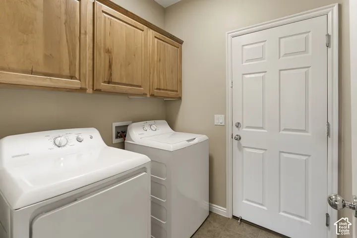 Utility room featuring light wood-finish cabinetry, a six-panel door, and integrated laundry hookups