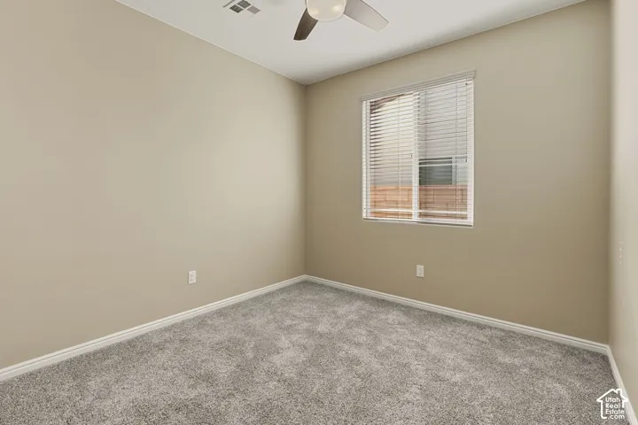 Neutral-toned interior featuring wall-to-wall carpeting, a ceiling fan with integrated lighting, and a window with horizontal blinds