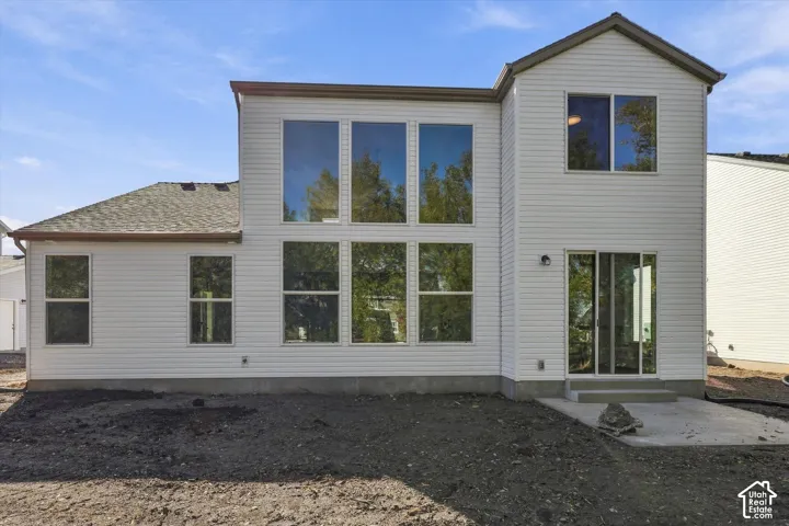 Multi-level exterior featuring horizontal siding, asphalt shingle roofing, large floor-to-ceiling windows, and a concrete patio