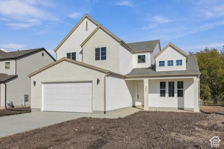 Multi-level exterior featuring light-toned brick masonry, stucco-style siding, a multi-gabled roofline, and an attached two-car garage