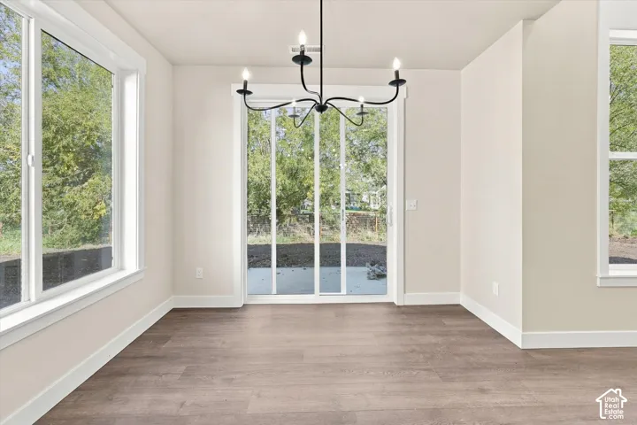 Interior space featuring wood-finish flooring, large multi-pane windows, a sliding glass door, and an overhead iron chandelier
