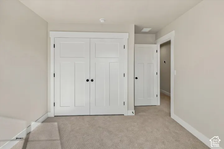 Neutral-toned interior featuring carpeted flooring, white paneled doors with matte black hardware, and crisp white door casing