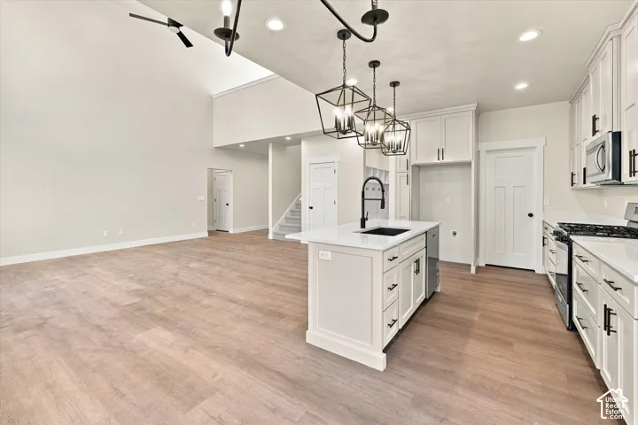 Kitchen featuring white cabinetry, an island with a quartz countertop, wood-finish flooring, vaulted ceilings, and matte black pendant lighting