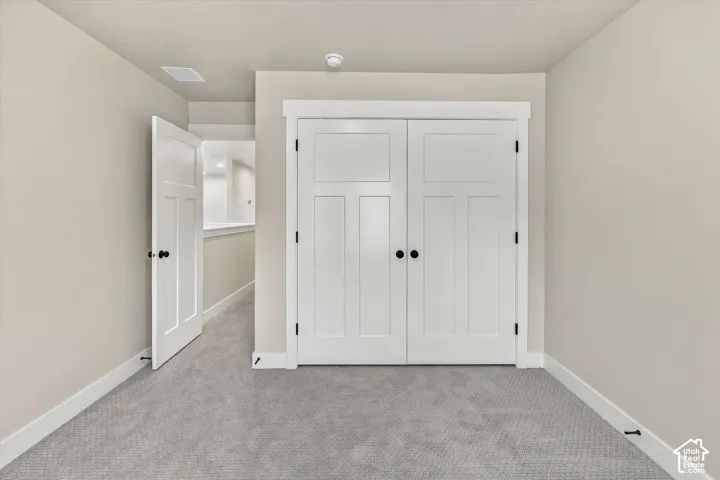 Interior room featuring neutral wall paint, textured carpeting, crisp white trim, double-panel closet doors, and matte black hardware