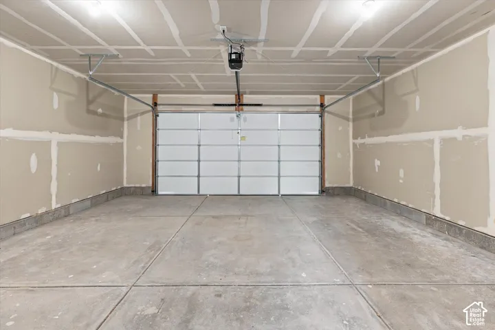 Multi-car garage featuring a concrete floor, high ceiling, overhead automatic door opener, and finished-ready interior walls