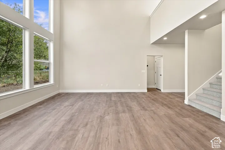 Vaulted ceilings, expansive floor-to-ceiling windows, wood-finish flooring, recessed lighting, and carpeted staircase