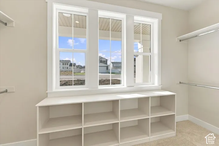 Walk-in closet featuring triple-pane windows, built-in open shelving, and metal closet rods
