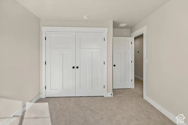 Neutral wall color, wall-to-wall carpeting, white shaker-style double closet doors, and interior doors featuring crisp white trim