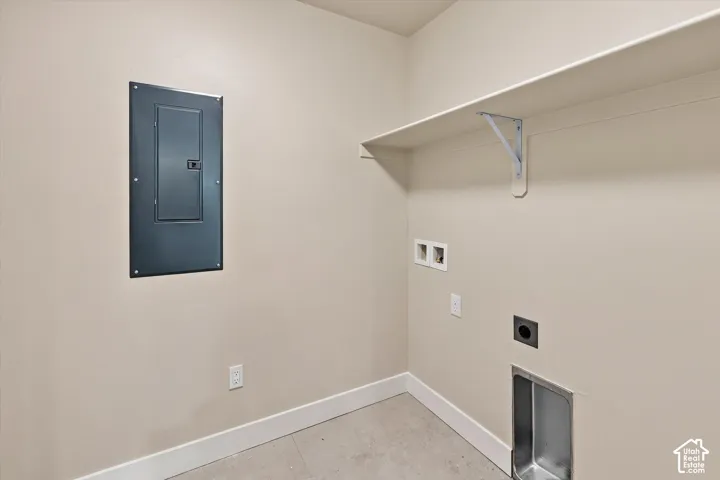 Service area featuring a recessed electrical panel, wall-mounted shelving with support brackets, and utility plumbing hookups
