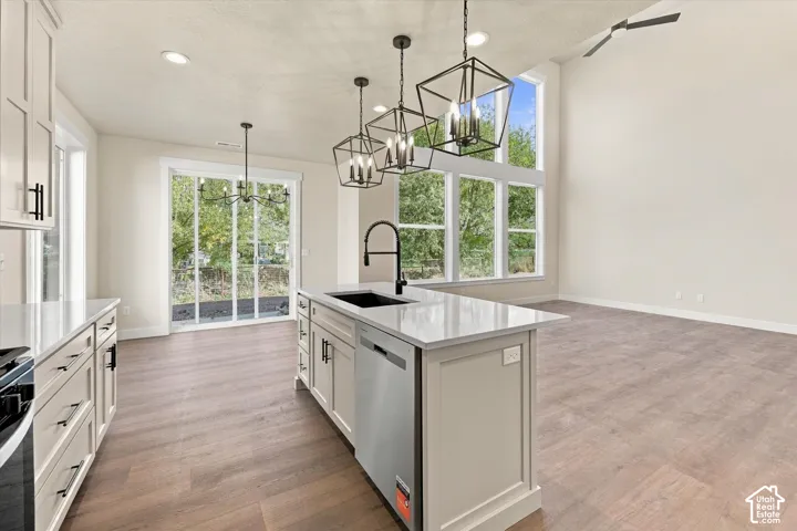 Open-concept kitchen and living area featuring high ceilings, wood-finish flooring, a center island with quartz countertops, custom cabinetry, and large, multi-pane windows