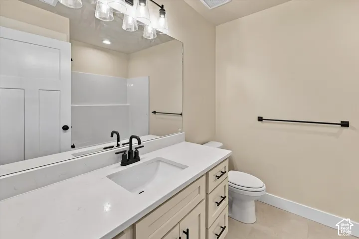 Bathroom featuring a stone-surface countertop with an integrated basin, matte black faucet and hardware, shaker-style vanity cabinetry, and a full-width wall mirror with integrated multi-bulb vanity lighting