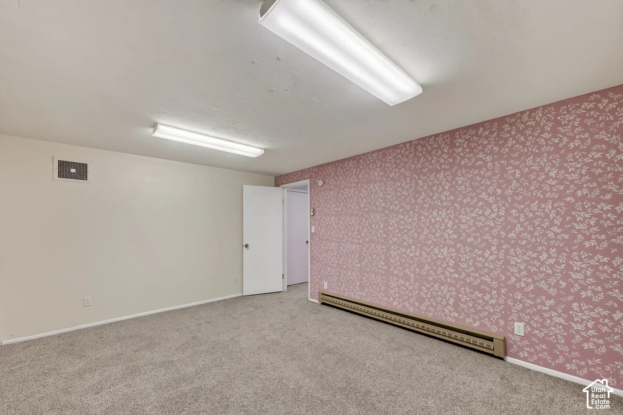 Room featuring patterned wallpaper, neutral carpeting, and dual rectangular overhead light fixtures