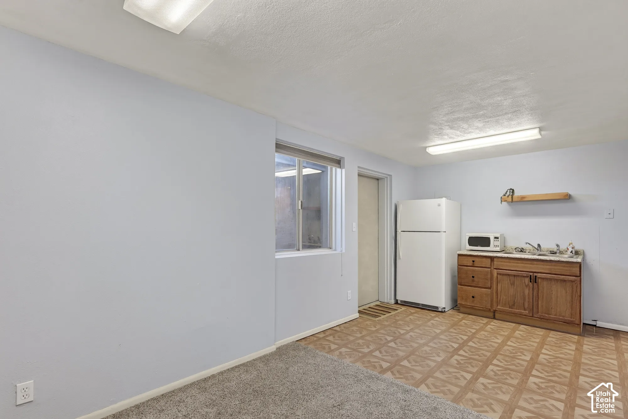 Kitchenette area featuring wood cabinetry, laminate flooring, a recessed window, and wall-mounted shelving
