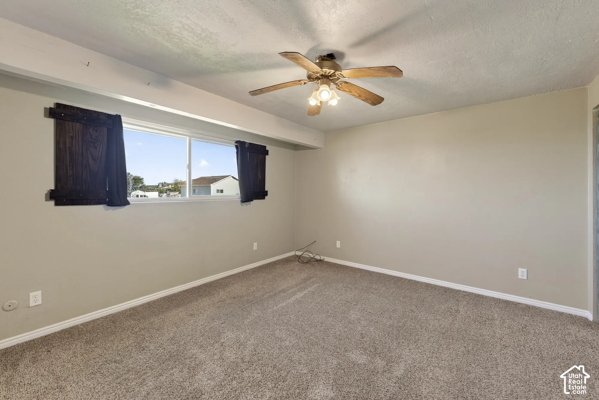 Room featuring neutral wall tones, wall-to-wall carpeting, a large sliding window, and a ceiling fan with integrated lighting