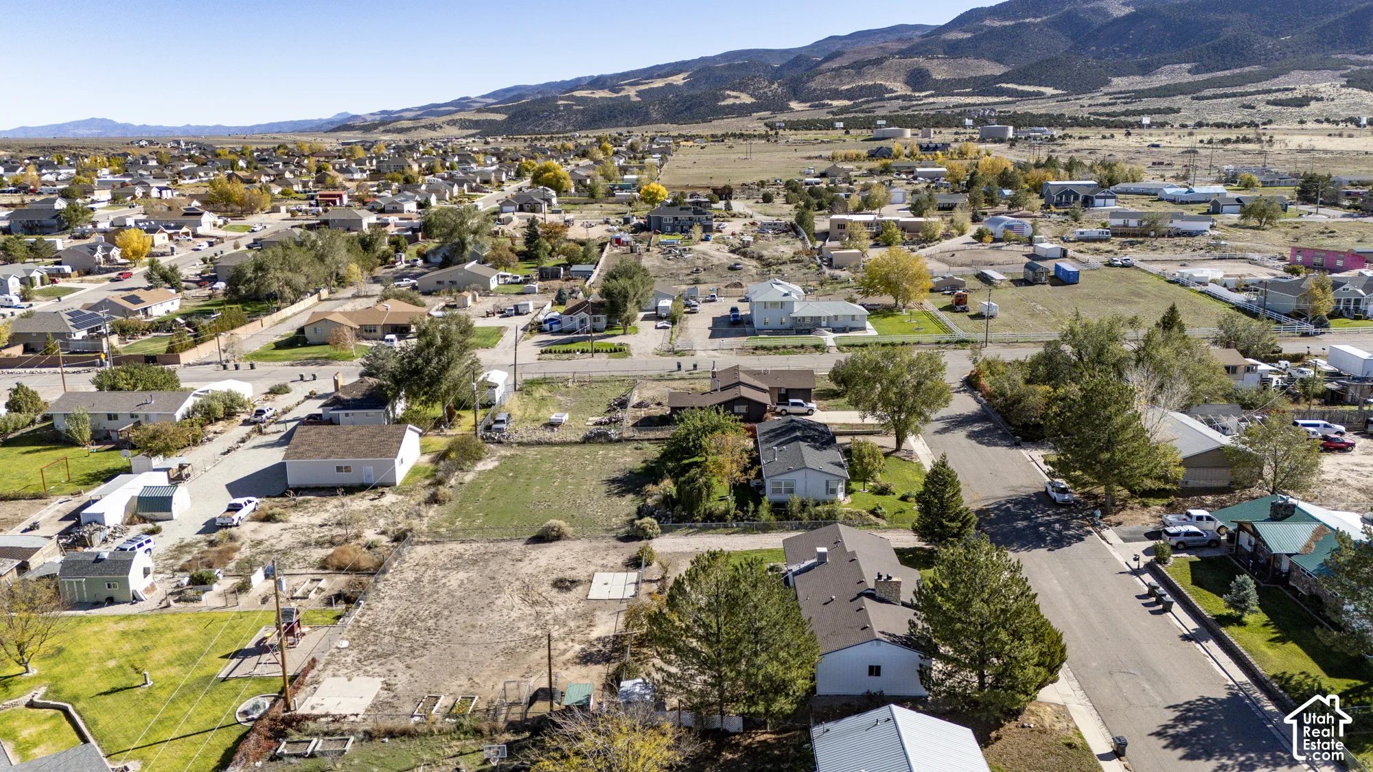 Aerial perspective of the property featuring a rectangular lot, mature trees, and mountainous terrain in the distance