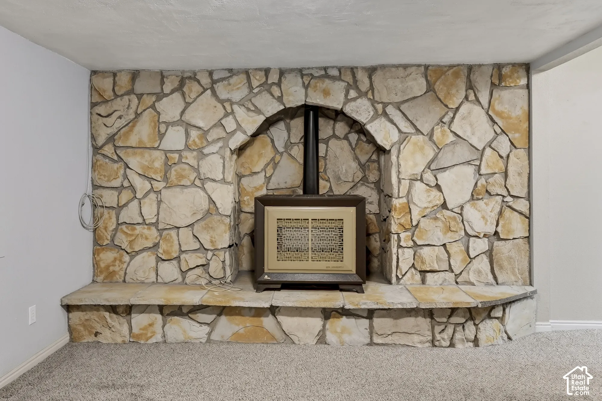 Full-height natural stone accent wall featuring an arched niche and a raised stone hearth with a built-in heating unit