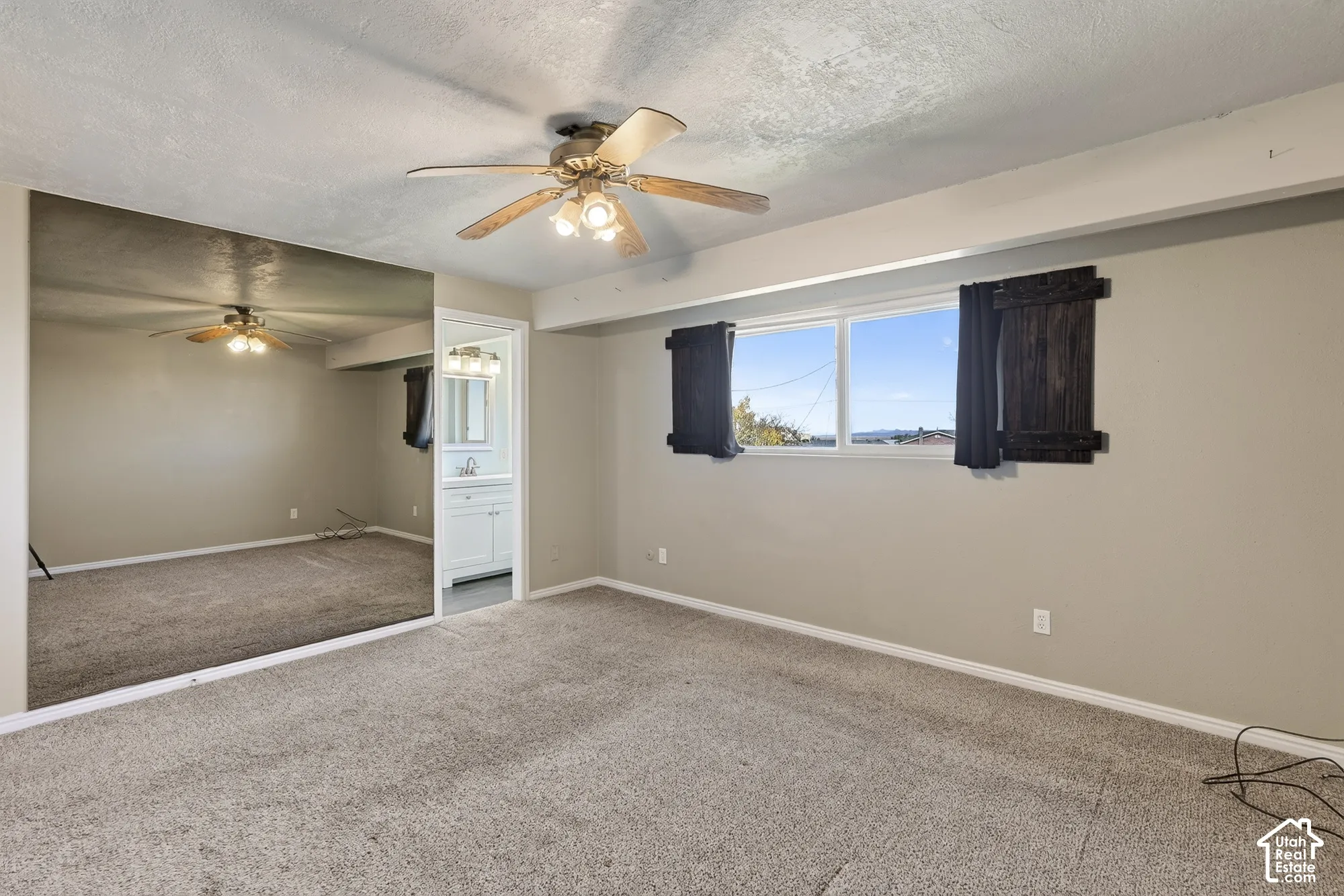 Room featuring wall-to-wall mirrored paneling, carpeting, dual-pane window, and a ceiling fan with integrated lighting