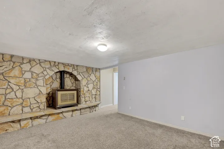 Interior space featuring a floor-to-ceiling flagstone accent wall with an integrated raised stone hearth and a built-in metal stove, complemented by a textured ceiling and flush-mount lighting