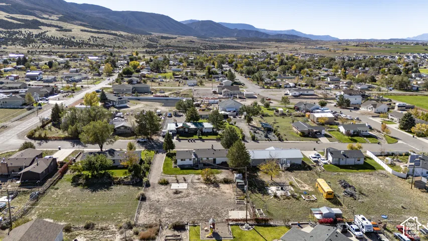 Aerial perspective of the property featuring expansive open lot space, established perimeter fencing, and prominent mountain backdrops