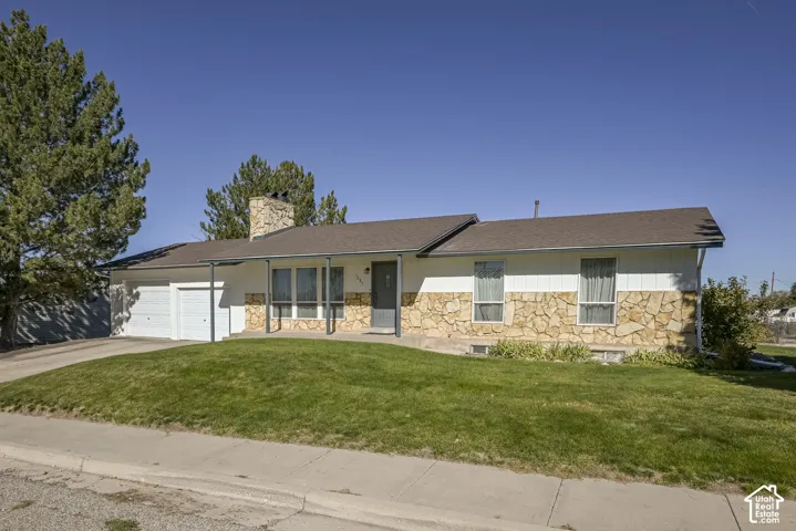 Single-level exterior featuring a stone masonry facade, horizontal siding, attached two-car garage, and a chimney