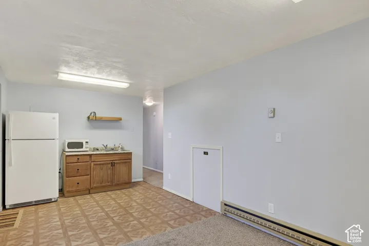 Kitchenette area featuring wood cabinetry, stone-finish countertops, a wall-mounted shelf, and patterned vinyl flooring