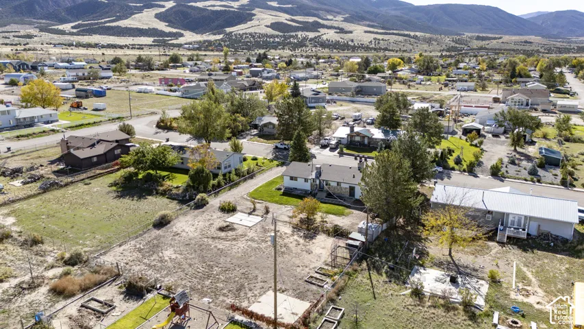 Aerial perspective featuring a spacious lot with mature trees and a prominent mountain range backdrop