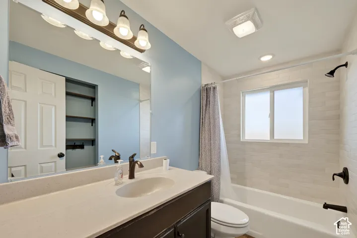 Bathroom featuring a vanity with a solid-surface countertop, an integrated oval sink, horizontal tile surround in the shower area, and built-in shelving