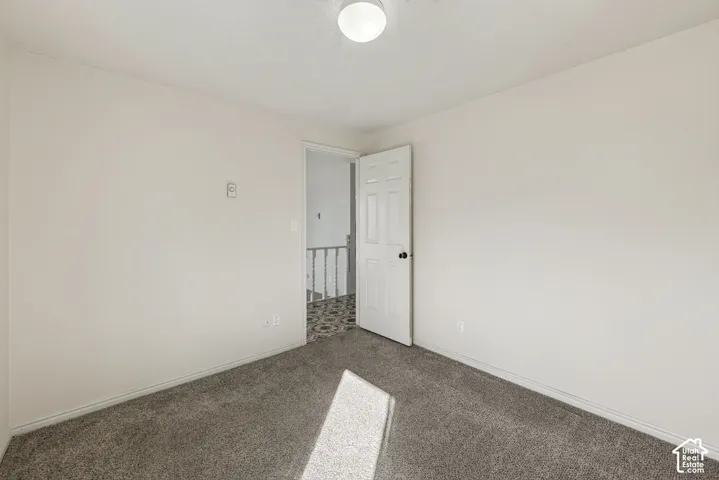 Neutral-toned wall finish, wall-to-wall carpeting, flush-mount ceiling light, and six-panel interior door